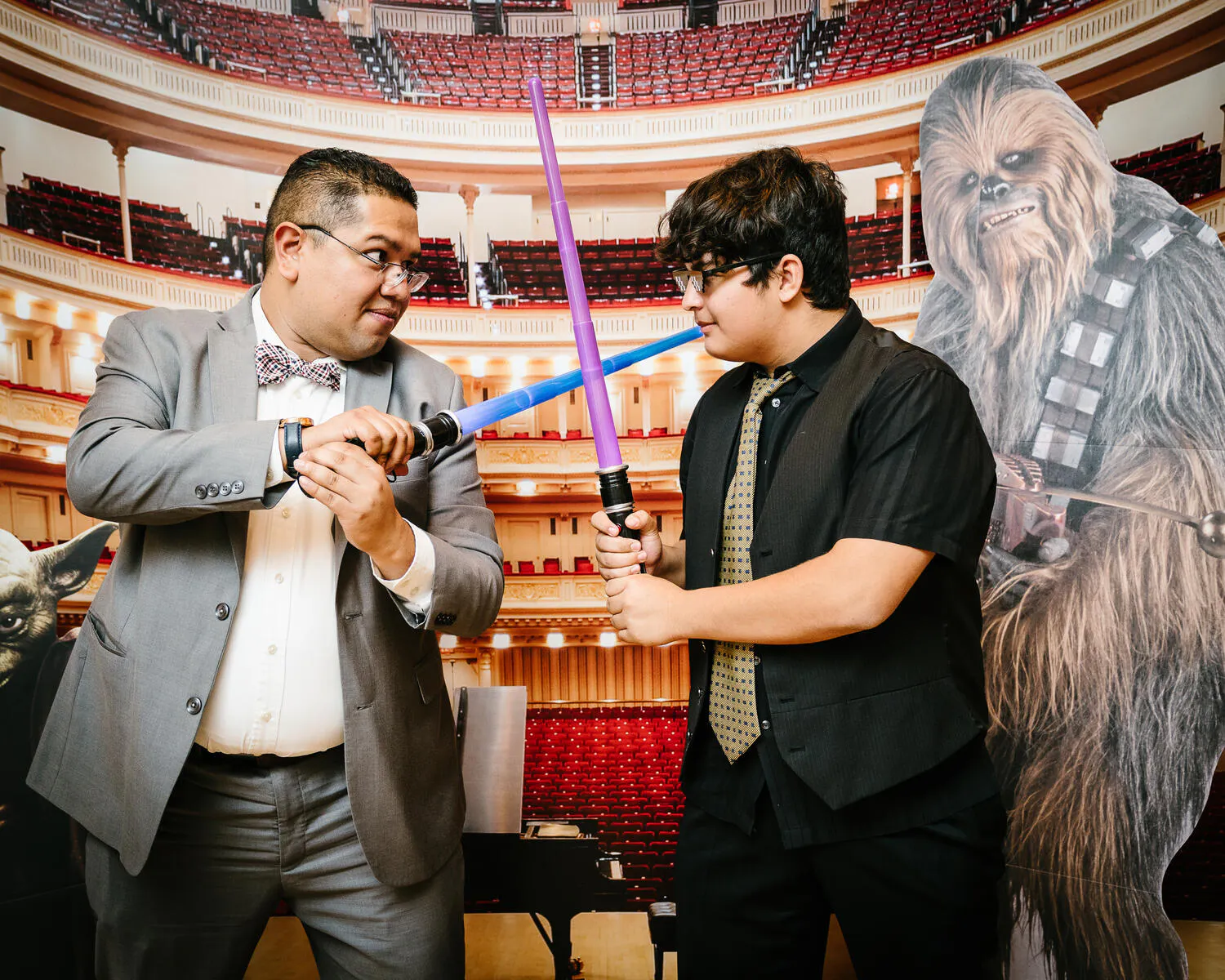 People posing against a backdrop of Carnegie Hall with Star Wars characters beside them.