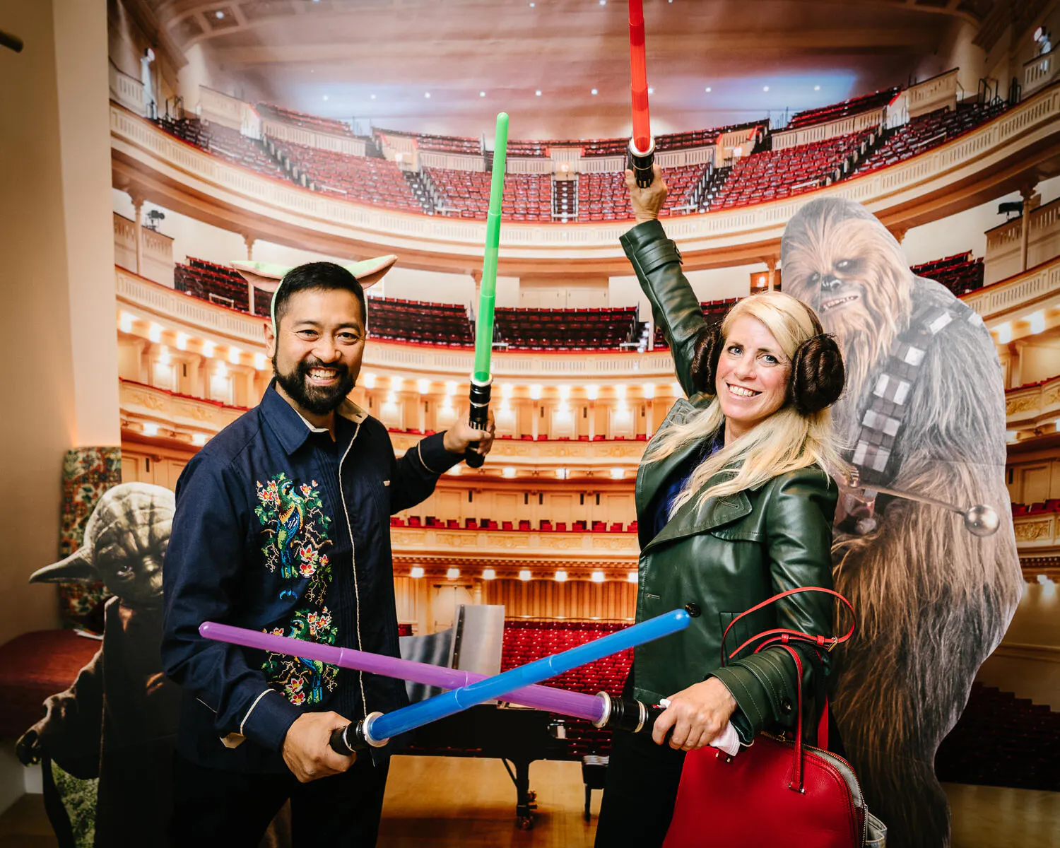 People posing against a backdrop of Carnegie Hall with Star Wars characters beside them.