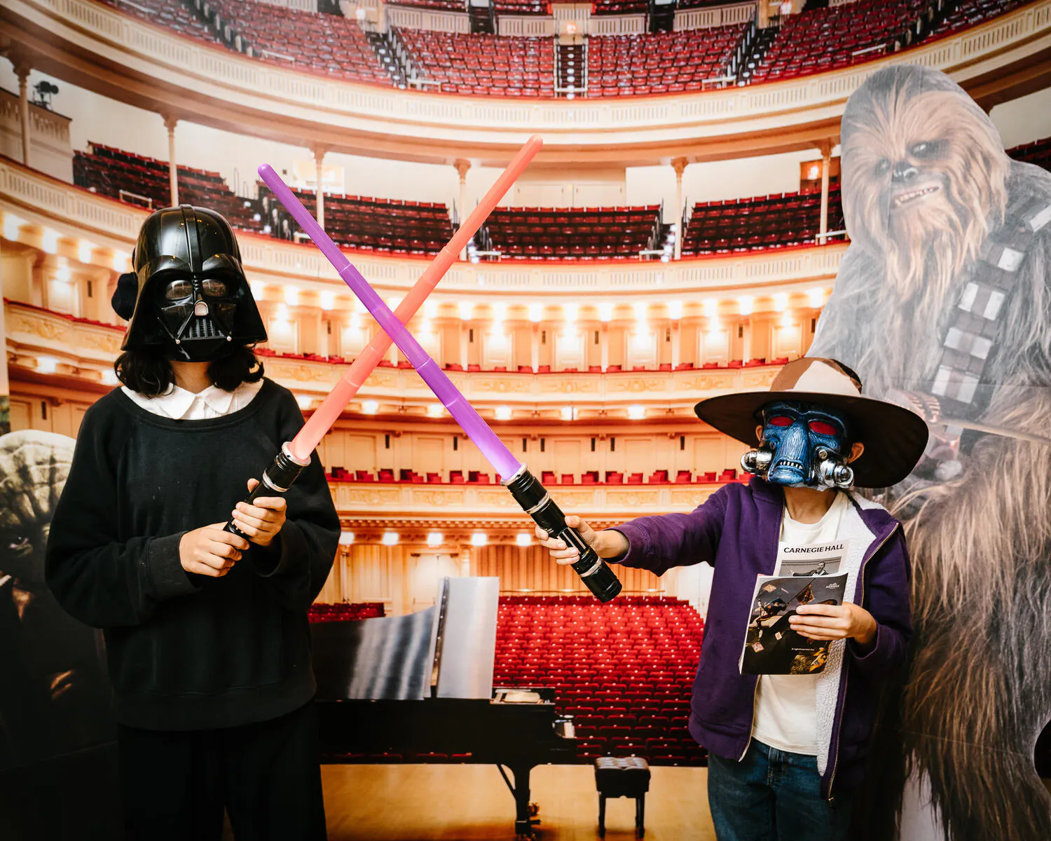 People posing against a backdrop of Carnegie Hall with Star Wars characters beside them.