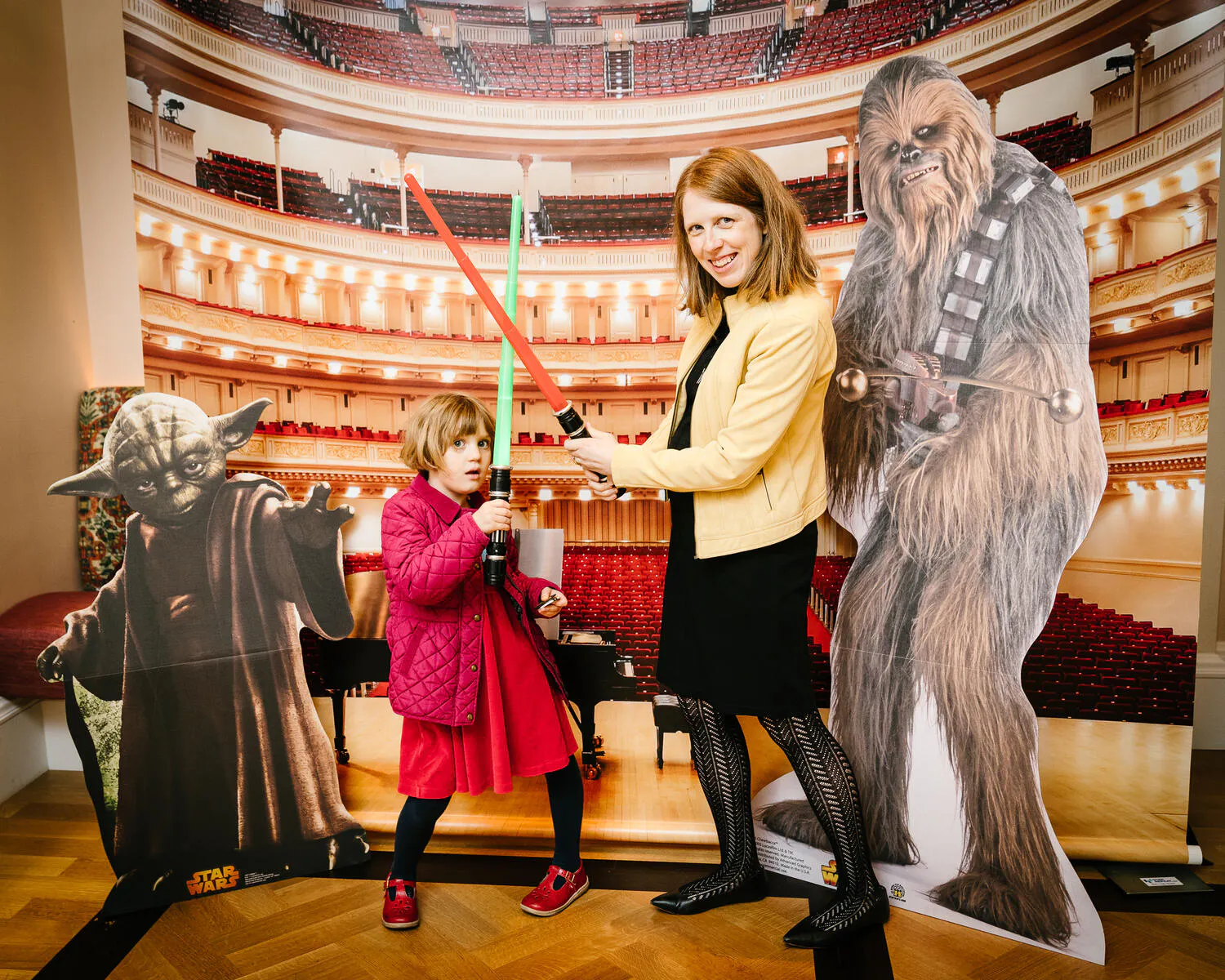 People posing against a backdrop of Carnegie Hall with Star Wars characters beside them.