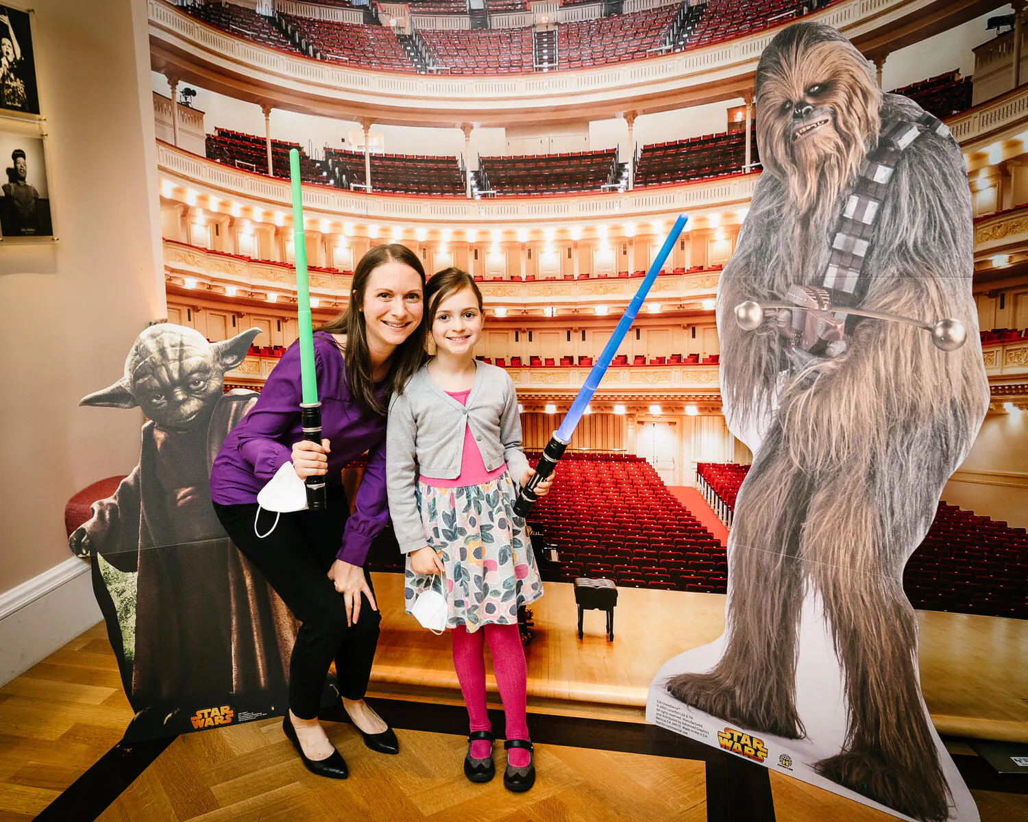 People posing against a backdrop of Carnegie Hall with Star Wars characters beside them.