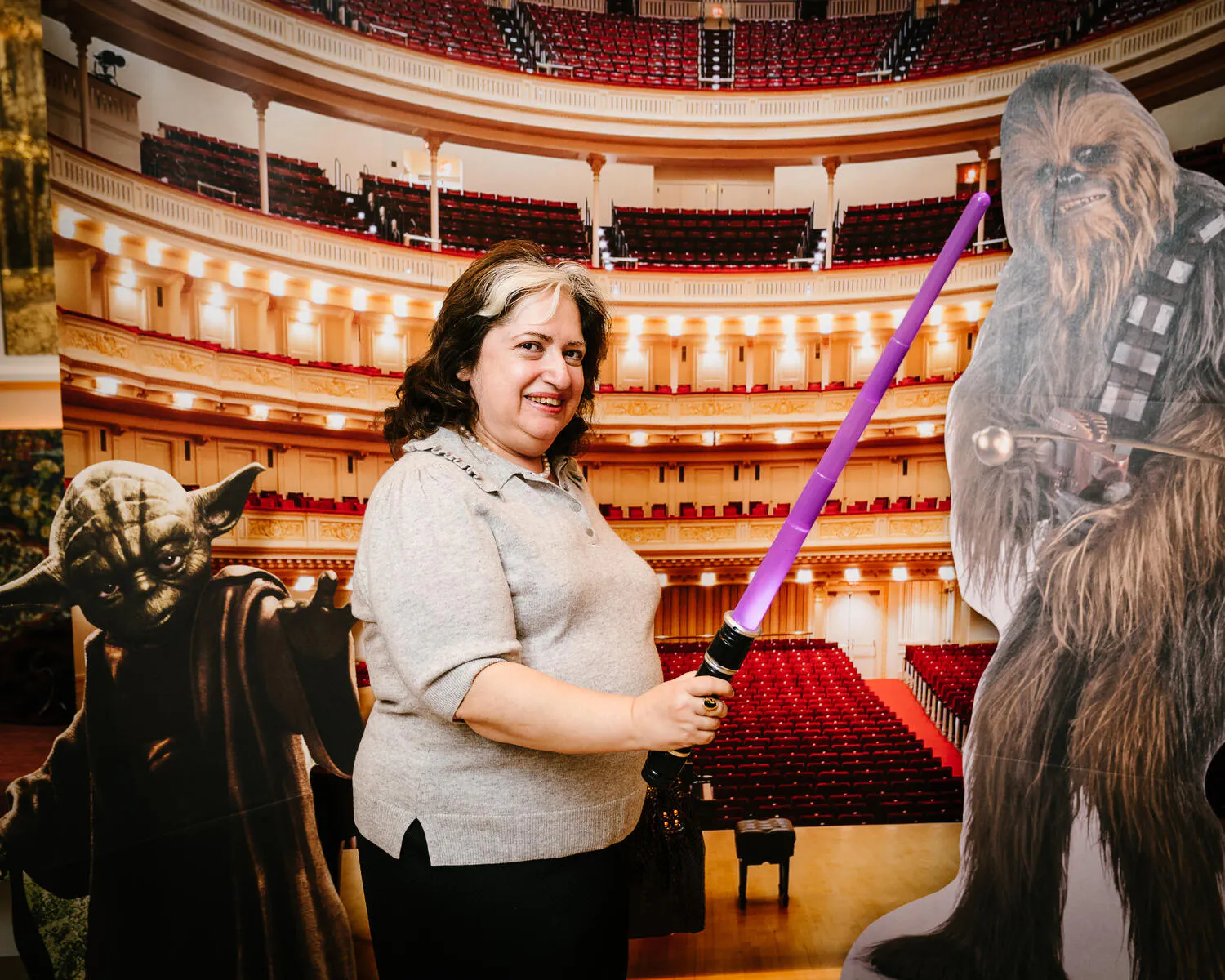A person posing against a backdrop of Carnegie Hall with Star Wars characters beside them.