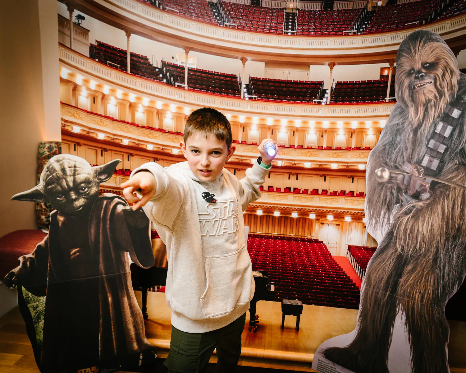 A person posing against a backdrop of Carnegie Hall with Star Wars characters beside them.