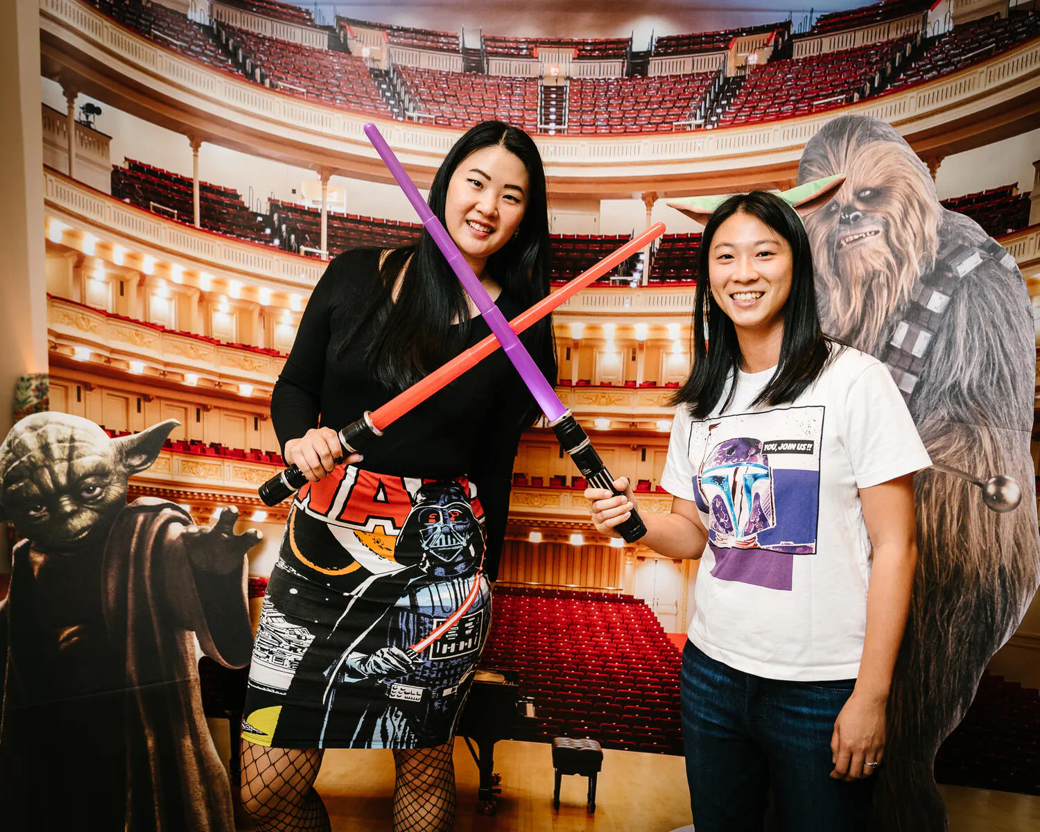 People posing against a backdrop of Carnegie Hall with Star Wars characters beside them.