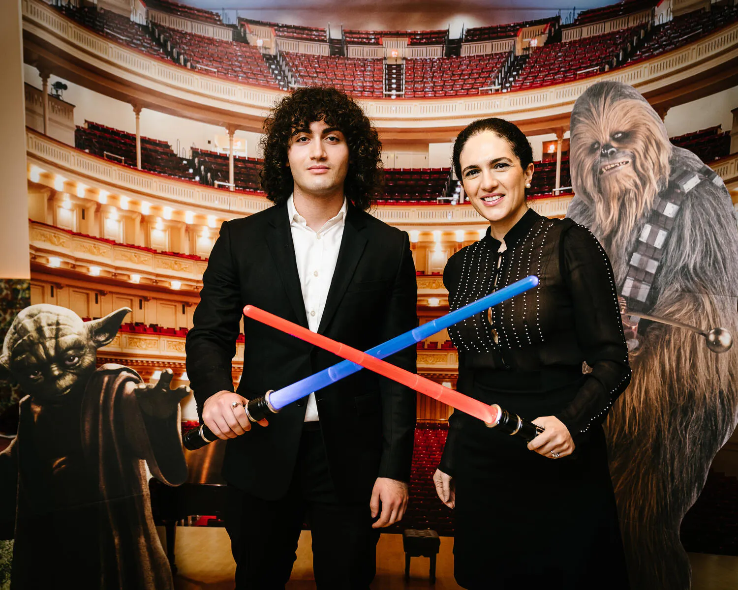 People posing against a backdrop of Carnegie Hall with Star Wars characters beside them.