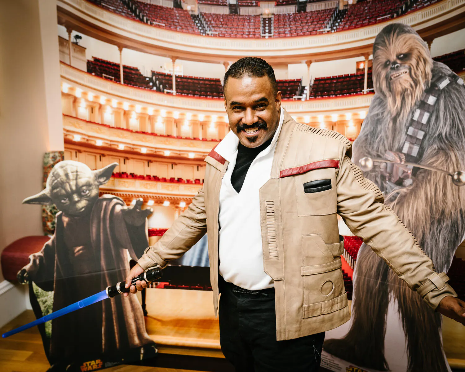 A person posing against a backdrop of Carnegie Hall with Star Wars characters beside them.
