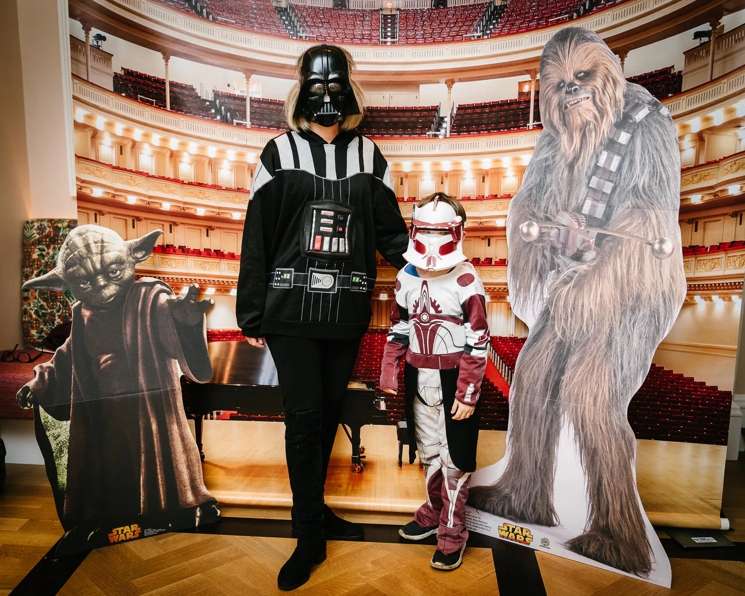 A person posing against a backdrop of Carnegie Hall with Star Wars characters beside them.