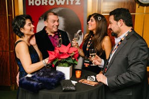 Four people stand around a cocktail table laughing