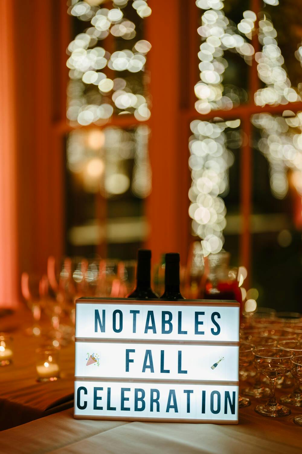 A sign reading "Notables Fall Celebration" lit up on a table