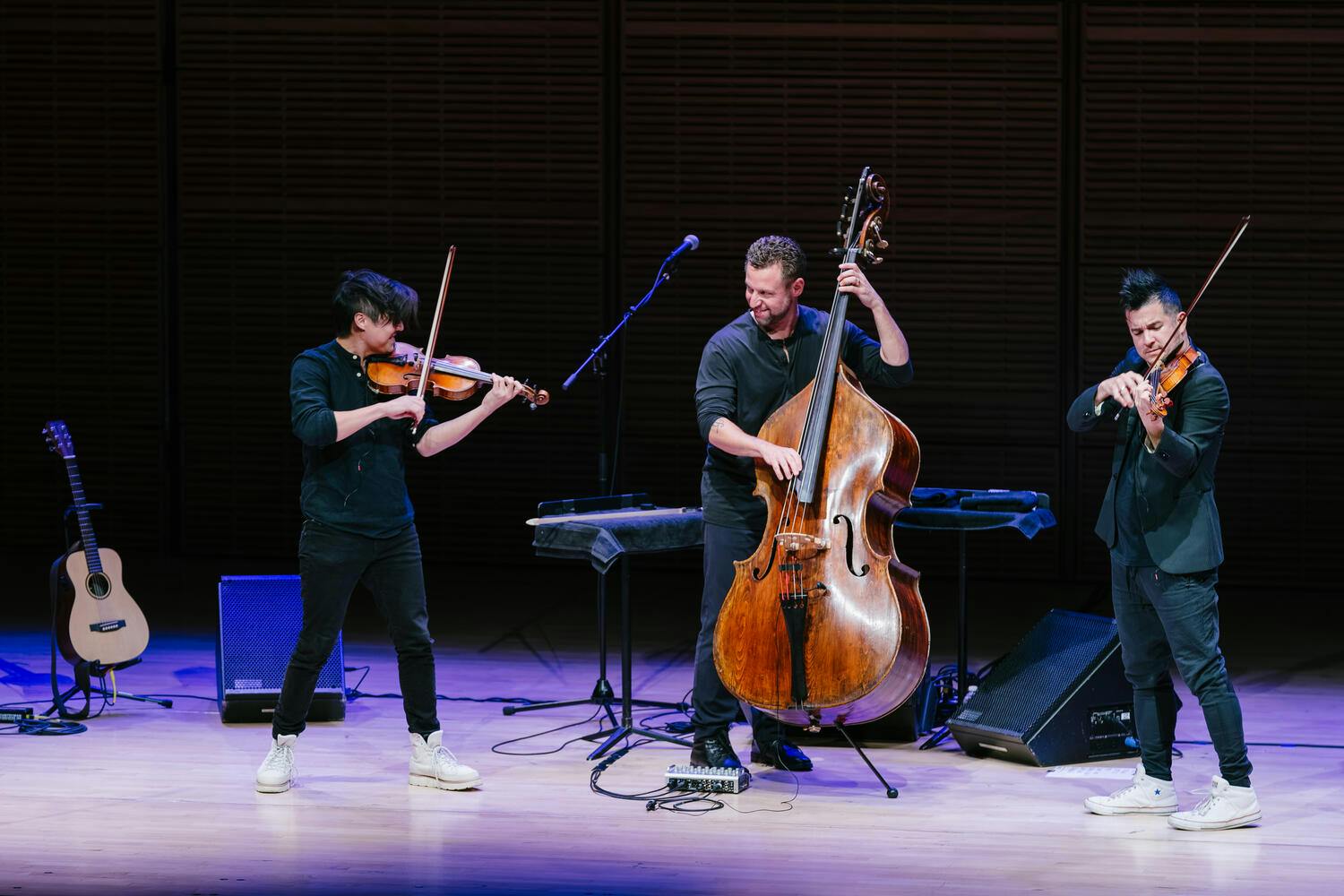 Two violinists and a bassist perform on stage