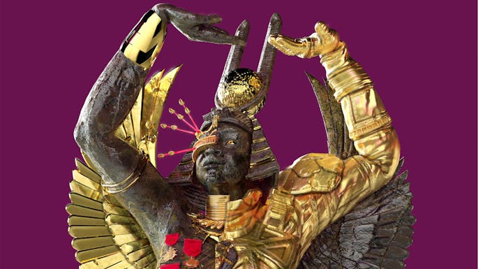 A black man with gold metal wings wearing an Egyptian headdress stands with arms upraised against a purple clouded sky