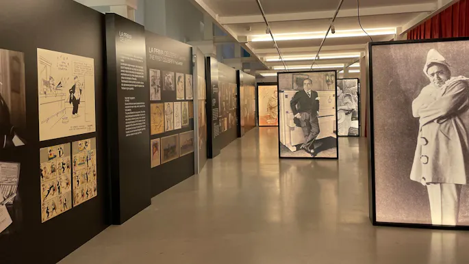 Museum exhibit with a large photo of Enrico Caruso wearing a suit and a photo of a man dressed as the Pierrot character
