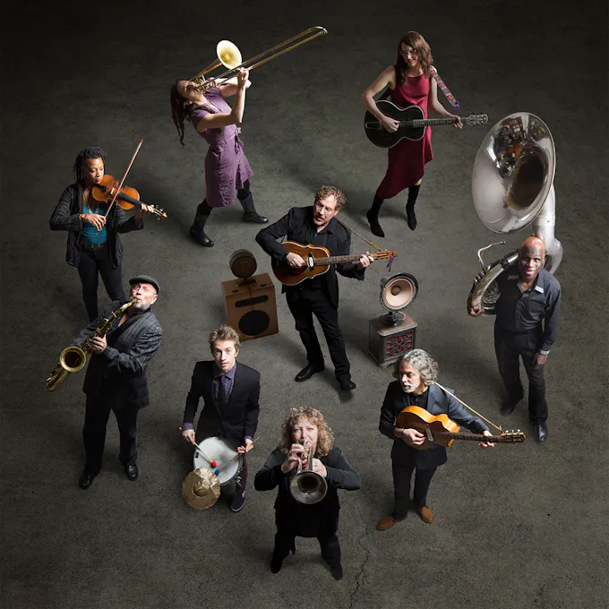 Hazmat Modine standing in a circle with instruments