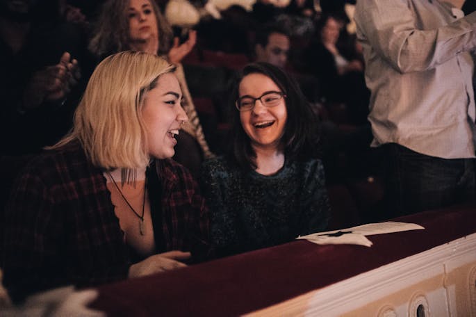 Two young women smile and laugh during a concert in Stern Auditorium / Perelman Stage.