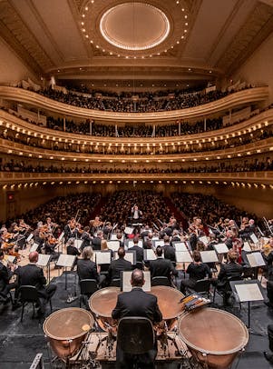 An orchestra on stage, with the audience behind them