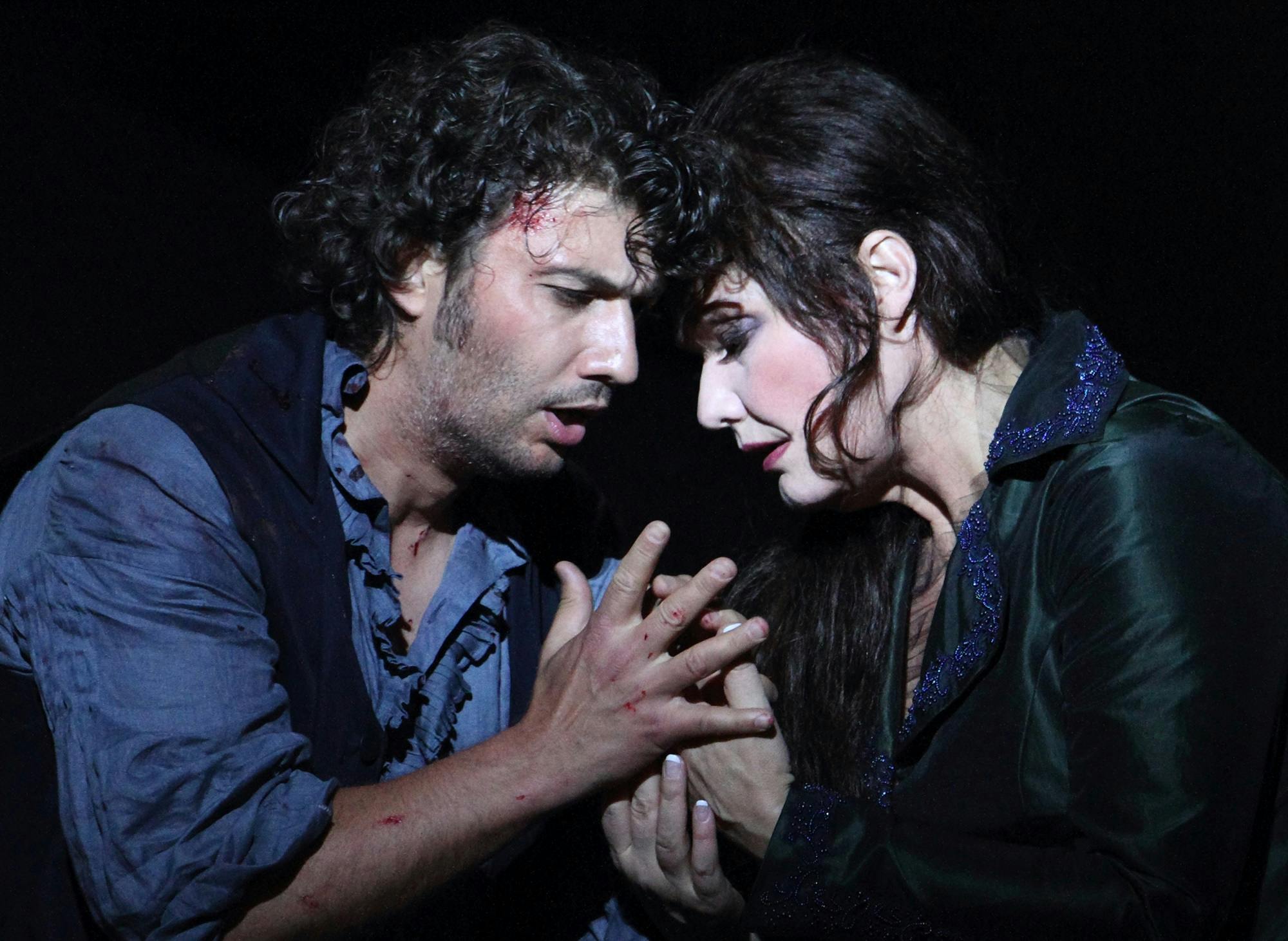 Jonas Kaufmann and Karita Mattila holding hands with their heads touching one another.