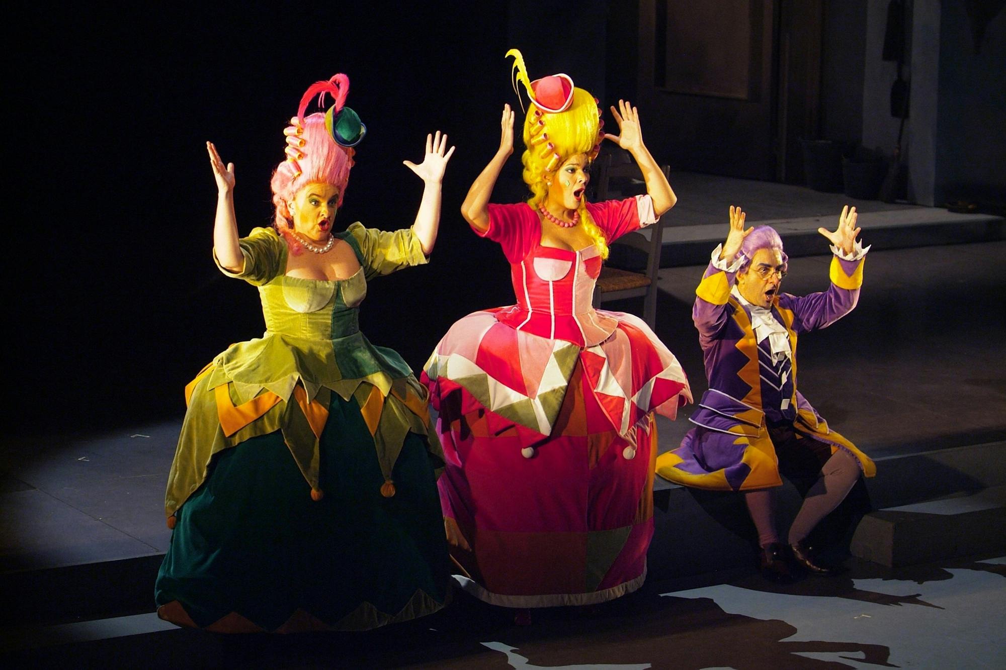 Two performers standing and one performer kneeling, all with arms raised in the air