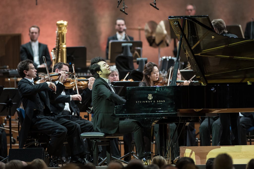 Lang Lang playing the piano with an orchestra.