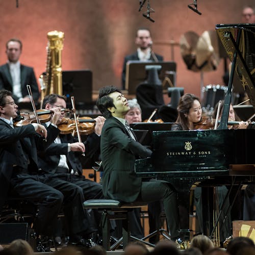 Lang Lang playing the piano with an orchestra.