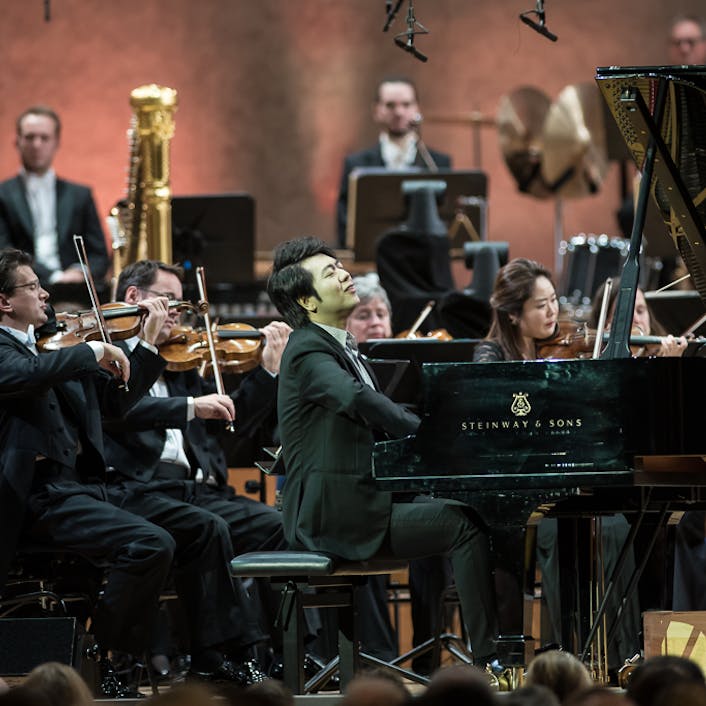 Lang Lang playing the piano with an orchestra.