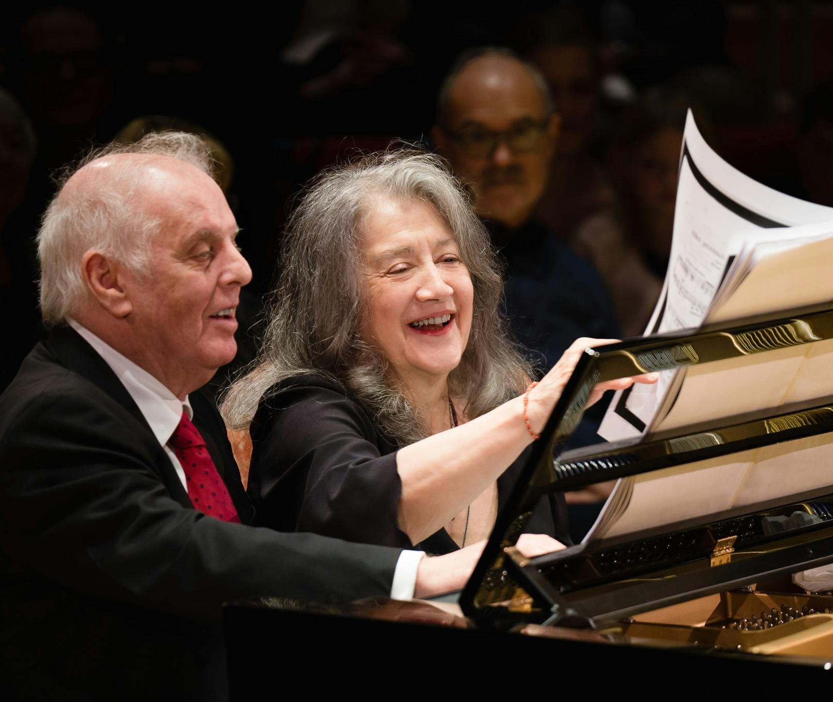 Daniel Barenboim and Martha Argerich turning a page of music at the piano.
