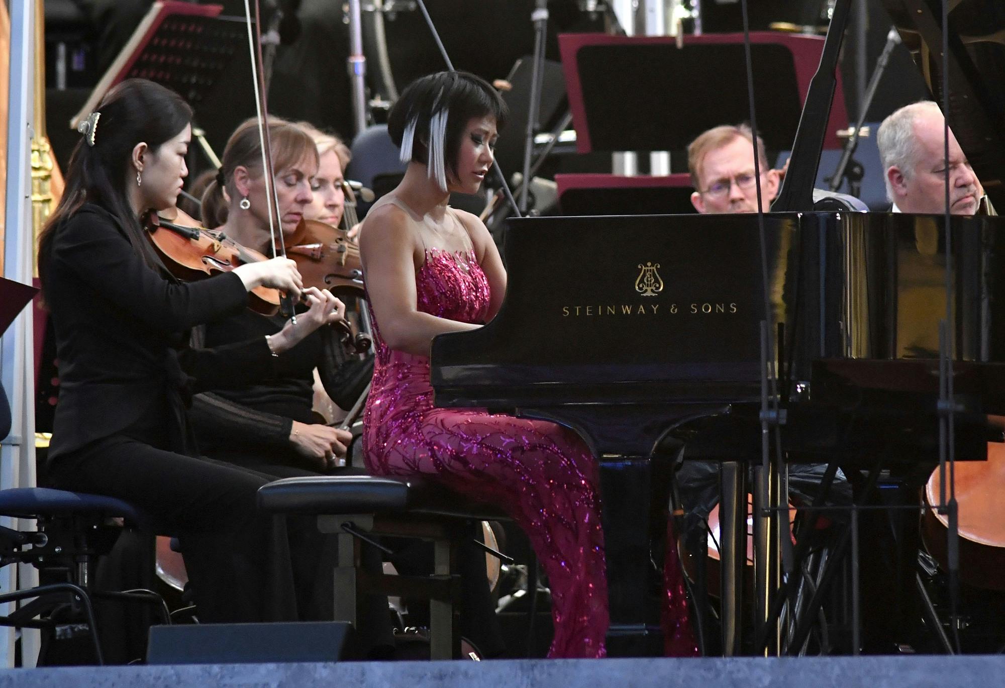 Yuja Wang playing the piano in front of an orchestra.