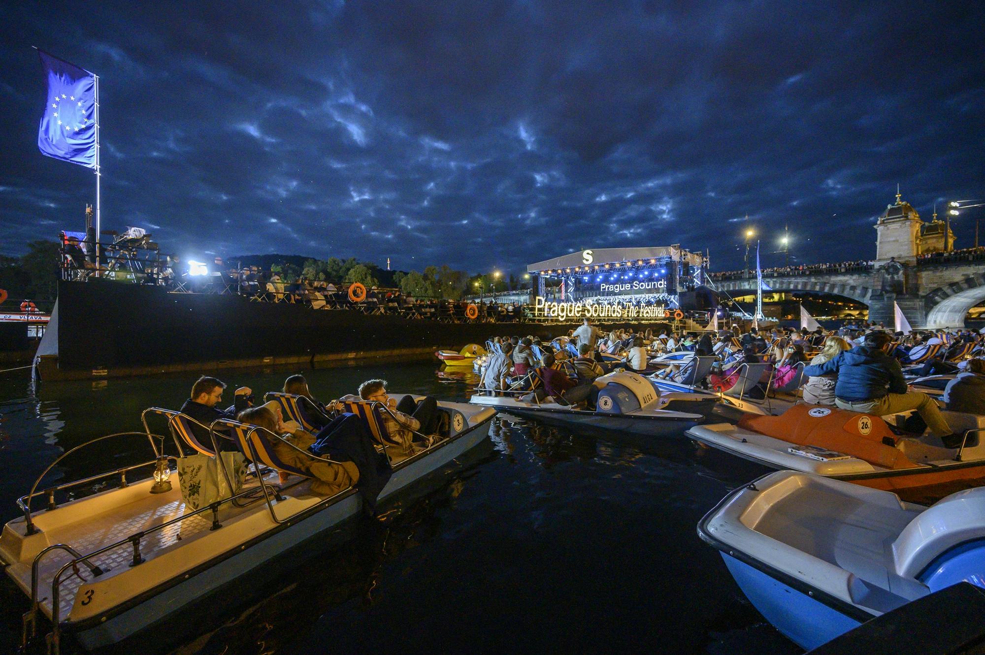 Audience members sitting on small boats in a river