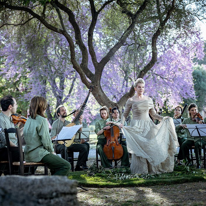 Joyce DiDonato and a chamber ensemble performing outdoors in front of a tree