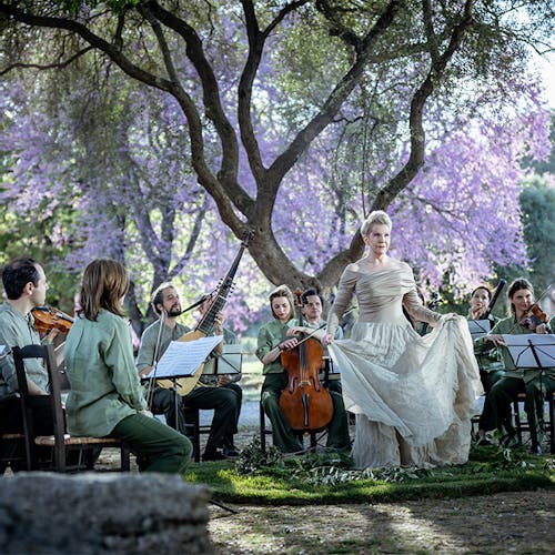 Joyce DiDonato and a chamber ensemble performing outdoors in front of a tree