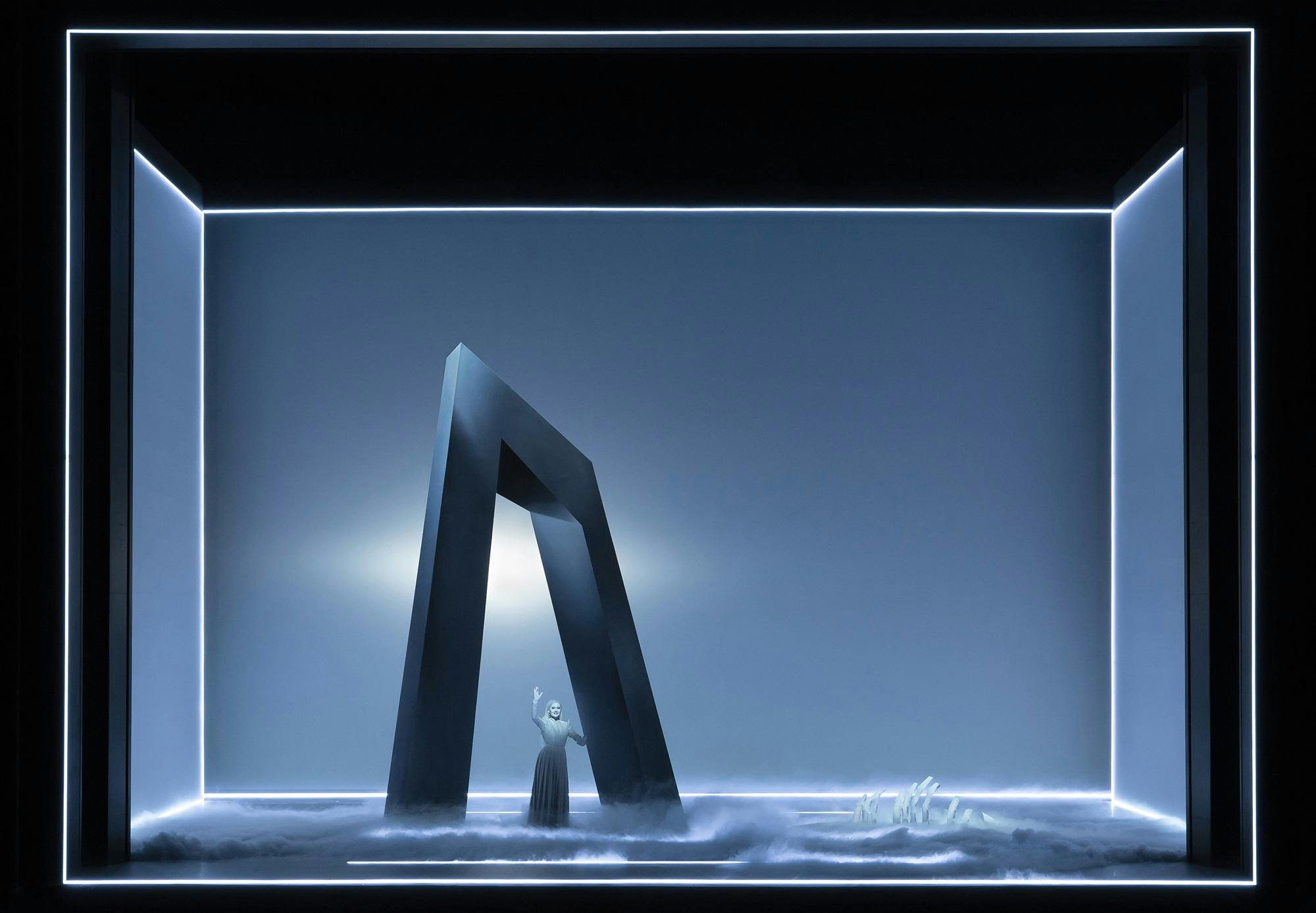 An actor standing underneath a large structure shaped like the letter A, surrounded by fog