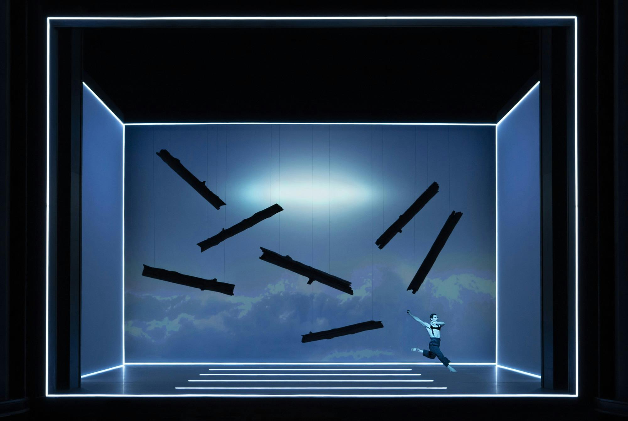 An actor jumping in the air, with dark rectangular shapes suspended in the air
