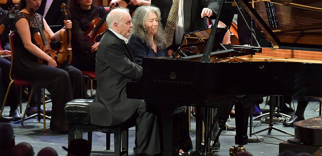Daniel Barenboim and Martha Argerich performing on the same piano with an orchestra