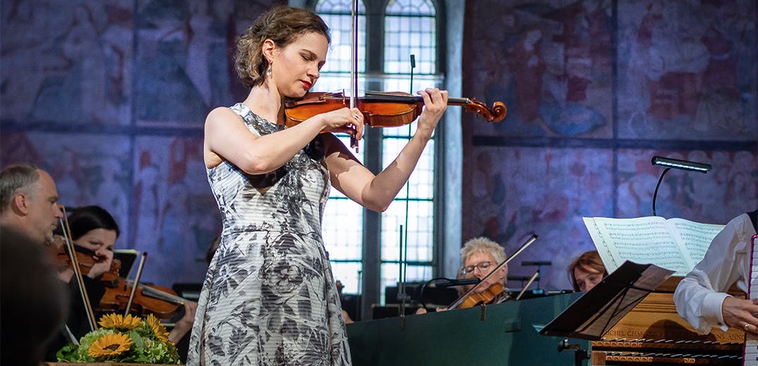 Hilary Hahn playing violin with an orchestra.