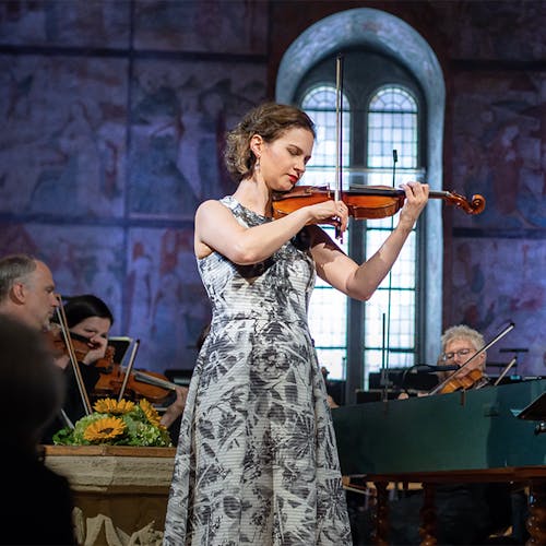 Hilary Hahn playing violin with an orchestra.