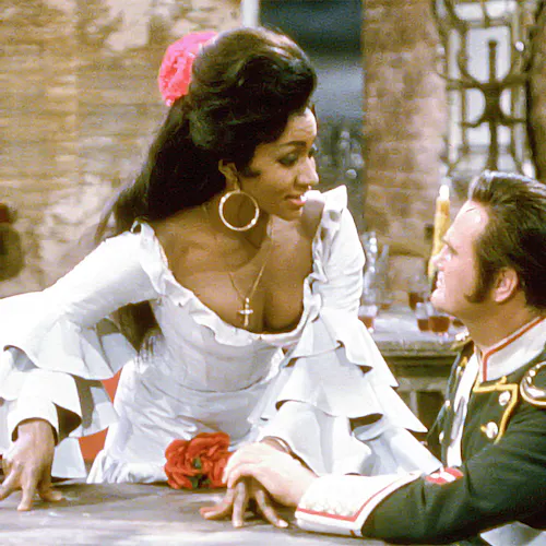 Grace Bumbry standing next to an actor sitting at a table