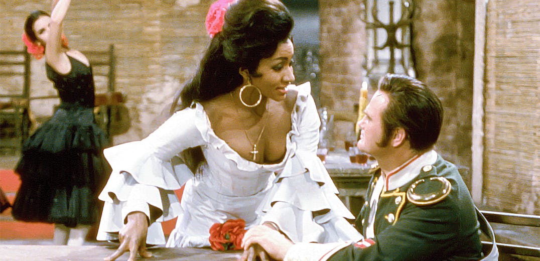 Grace Brumbry standing next to an actor sitting at a table