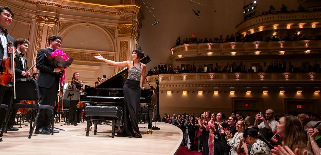 Yuja Wang and the NYO-USA All Stars standing on stage for applause