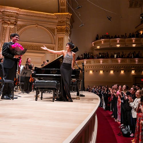 Yuja Wang and the NYO-USA All Stars standing on stage for applause