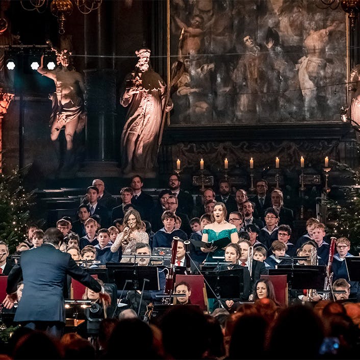 A vocalist, conductor, and musicians performing on stage