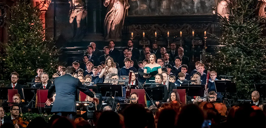 A vocalist, conductor, and musicians performing on stage