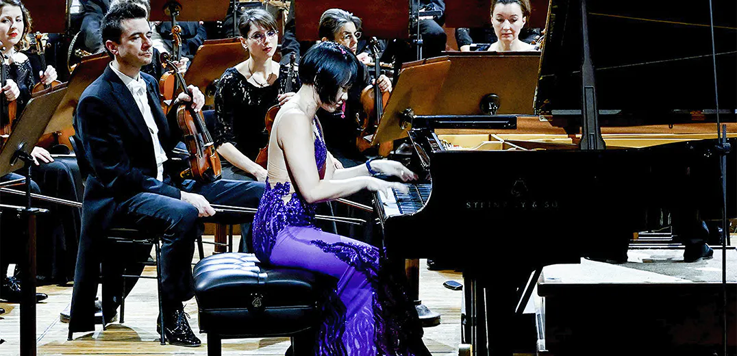 Yuja Wang playing the piano in front of an orchestra