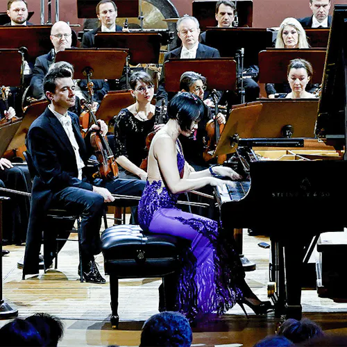 Yuja Wang playing the piano in front of an orchestra