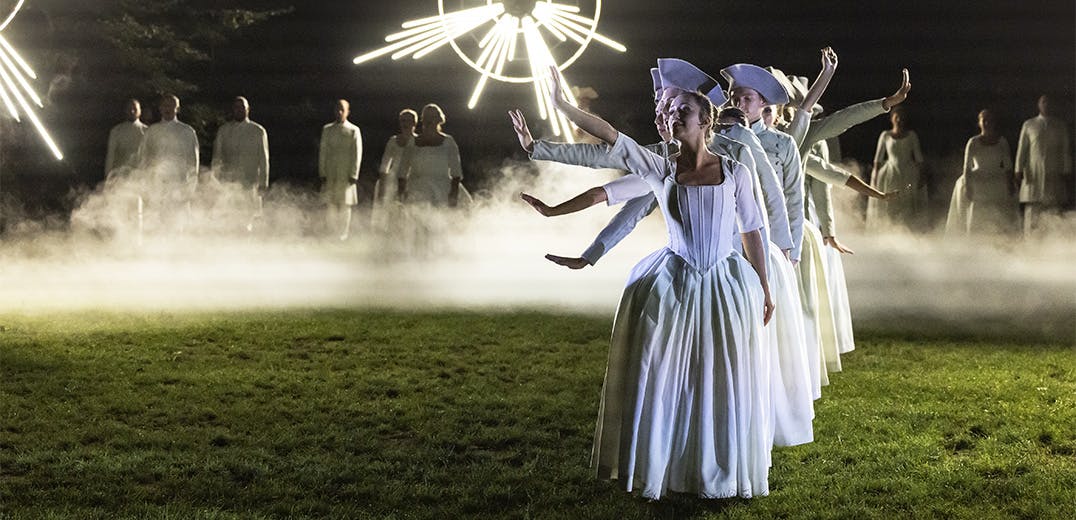 Dancers forming a line on a grass field on a foggy night