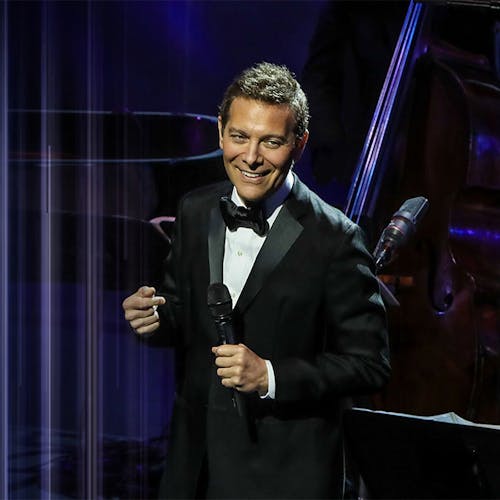 Michael Feinstein on stage holding a microphone
