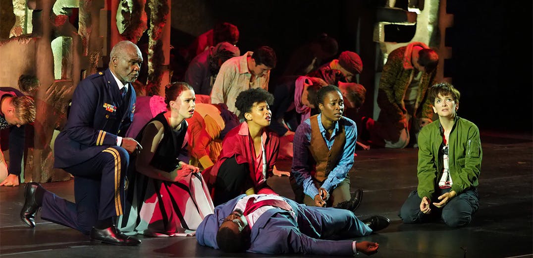 A group of people kneeling in front of a lifeless body