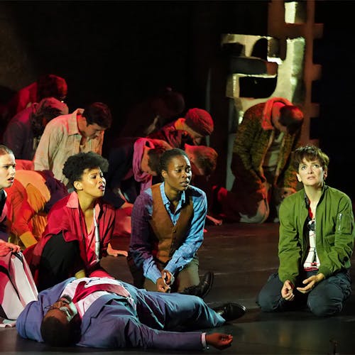 A group of people kneeling in front of a lifeless body