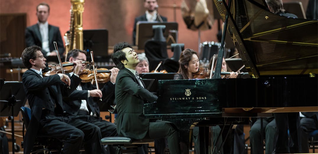 Lang Lang playing the piano with orchestra members