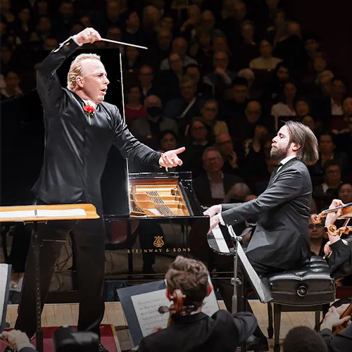 Yannick Nézet-Séguin conducting, Daniil Trifonov playing the piano, and a violinist playing the violin.