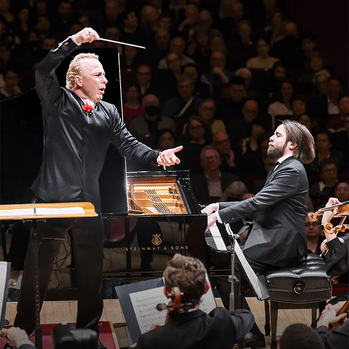 Yannick Nézet-Séguin conducting, Daniil Trifonov playing the piano, and a violinist playing the violin.