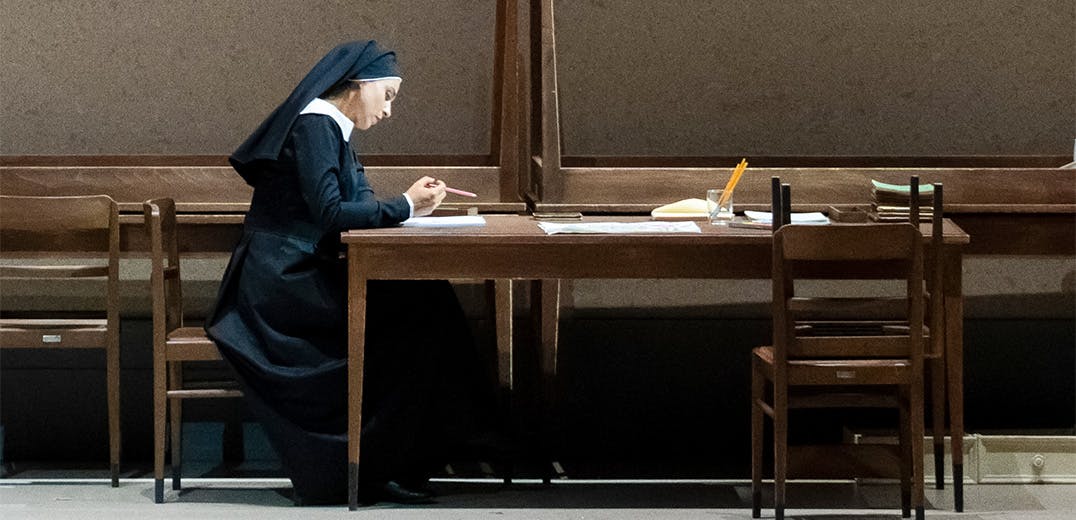 A nun sitting at a table reading a piece of paper